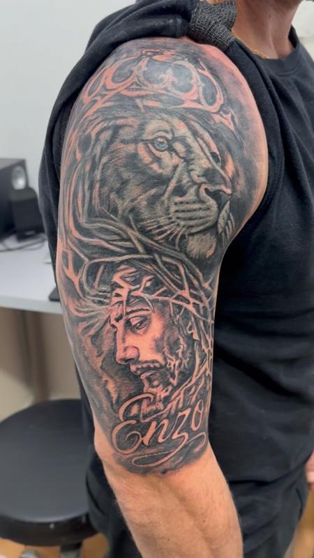 Cover up en el hombro: león con corona, Cristo con corona de espinas y el nombre Enzo en lettering
